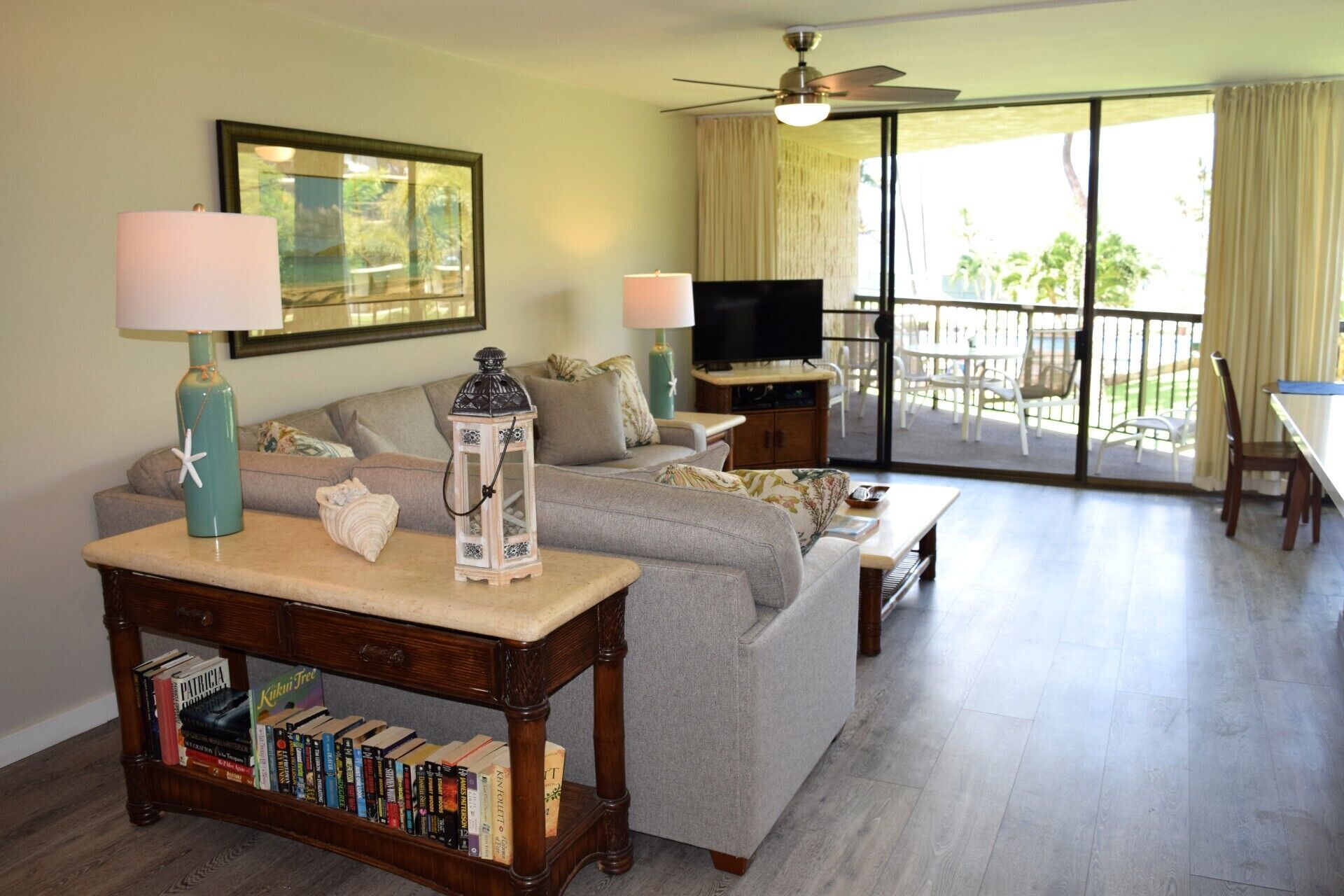 Un salon comprenant un canapé, une table basse, une bibliothèque, un téléviseur et un balcon aménagé avec du mobilier d’extérieur.