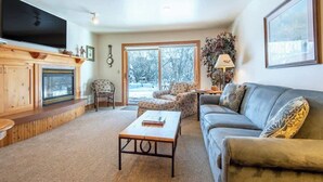 A cozy living room with a fireplace, a sofa, a coffee table, and a television.