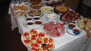 A table with various food items including bread, pastries, and meats, suggesting a buffet or communal dining setup. - La Biocca (Manciano)