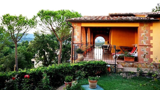 A house with a brick exterior, a tiled roof, and a small patio area with outdoor furniture. - La Biocca (Manciano)