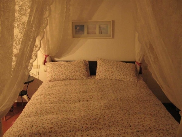 A bed with a floral bedspread, a bedside table, and a chair. - La Biocca (Manciano)