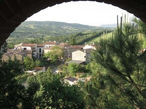 Une vue sur un village, encadrée par une arche, avec des bâtiments traditionnels et une végétation luxuriante.