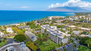 Un hotel costero con varias edificaciones, paneles solares en los tejados y vistas al océano y a las montañas.