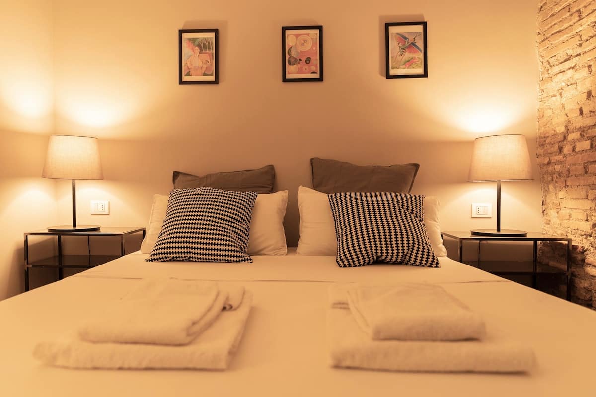 Une chambre d’hôtel avec un grand lit, deux tables de chevet avec des lampes et trois tableaux encadrés au mur.