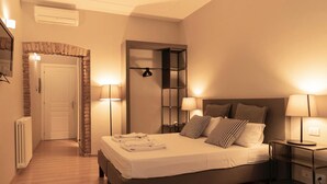 A bedroom with a bed, bedside lamps, a mirror, and a door leading to another room. - TrastevereInn (Rome)