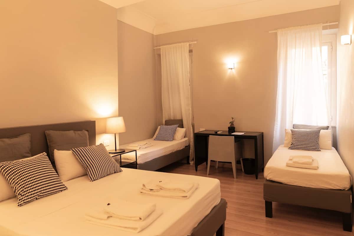 Une chambre d’hôtel avec deux lits, un bureau, une chaise et une petite table.