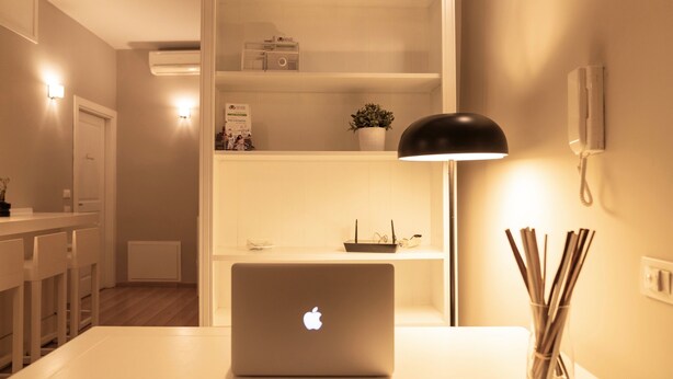 A modern kitchen with white cabinetry, a laptop on the counter, and a black lamp. - TrastevereInn (Rome)