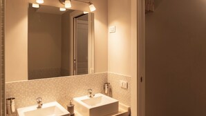 A bathroom with two sinks, a mirror, and a tiled backsplash. - TrastevereInn (Rome)