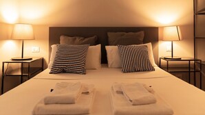 A hotel room with a neatly made bed, two bedside tables with lamps, and a headboard. - TrastevereInn (Rome)