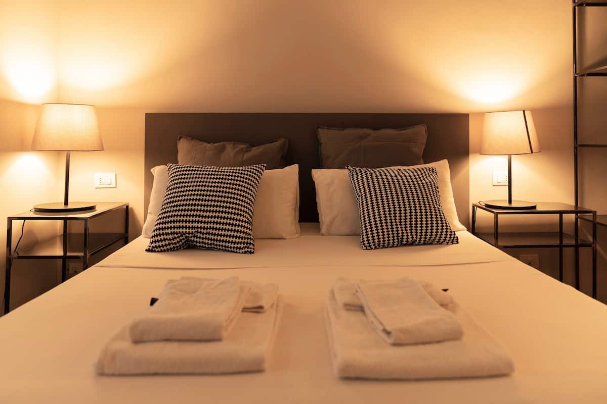 Une chambre d’hôtel avec un lit bien fait, deux tables de chevet avec des lampes et une tête de lit.