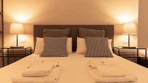 A neatly made bed with two pillows, two bedside tables with lamps, and a headboard. - TrastevereInn (Rome)