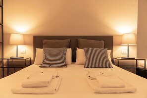 Una cama bien hecha con dos almohadas, dos mesitas de noche con lámparas y un cabecero.