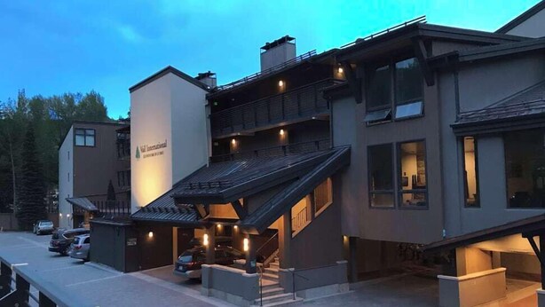 Un edificio de varios pisos con una entrada destacada, un espacio exterior cubierto y una escalera que conduce a los pisos superiores.