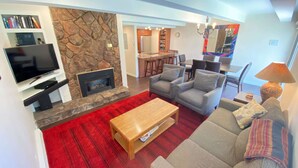Una sala de estar con pared de piedra, chimenea, televisor, sofá y mesa de centro.