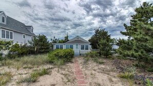 A pathway leading to a house with a beach view, surrounded by sand and vegetation. - 9819 Shore - Beachfront on Primehook Beach. (Milford)