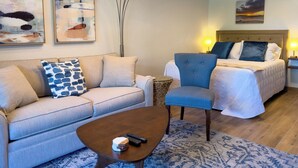 A modern hotel room with a sofa, armchair, and bed, featuring abstract wall art and a ceiling fan. - Newly remodeled studio, jacuzzi and pool (Kihei)