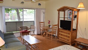 A room with a sofa, a dining table, chairs, a TV stand, and a ceiling fan.