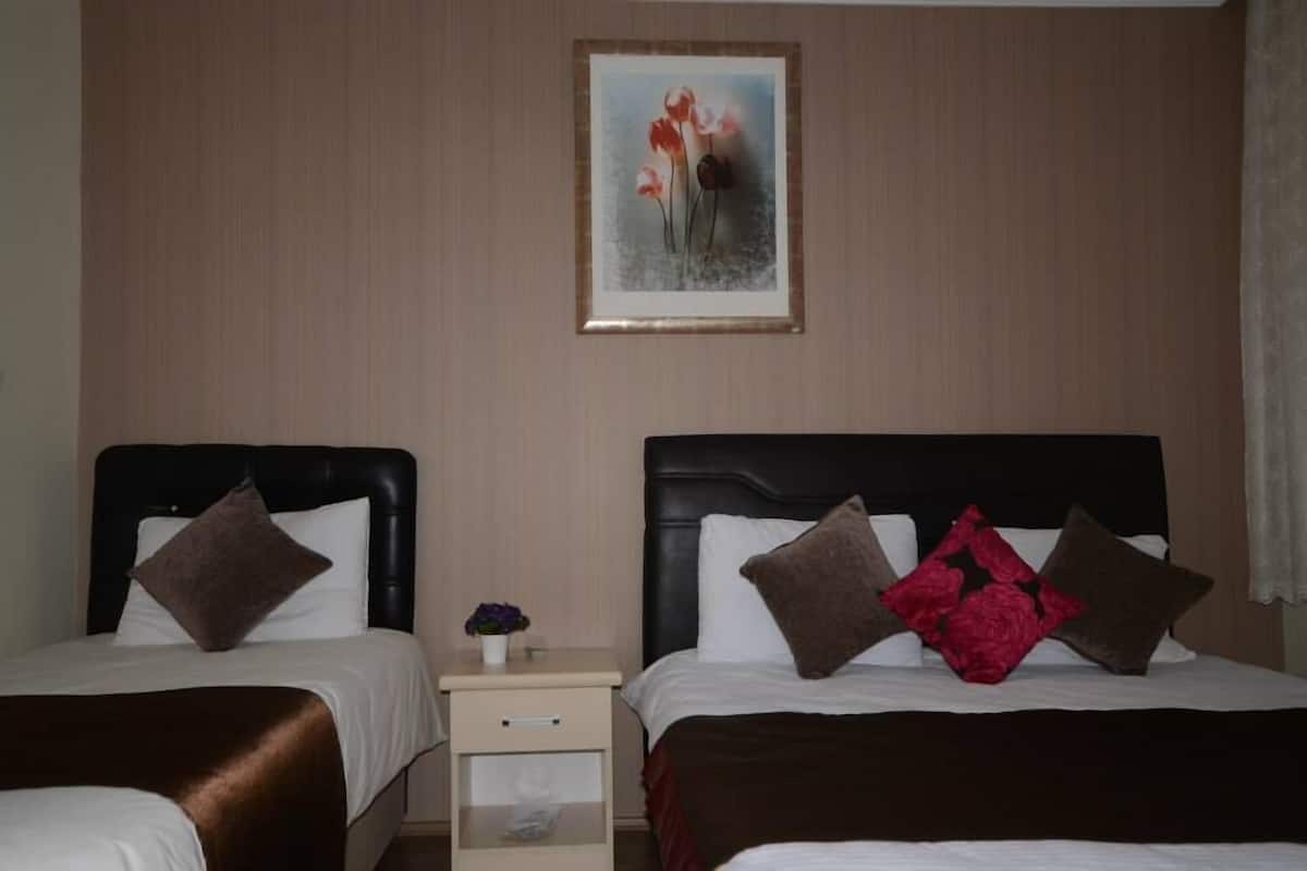 A hotel room with two beds, each with a headboard, a nightstand with a lamp, and a framed picture on the wall.