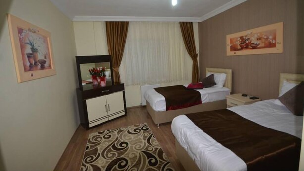 A hotel room with two beds, a dresser, a mirror, and a ceiling light. - Evrim Hotel (Hacibektas)