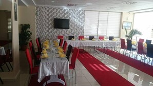 A dining area with tables set for a meal, red chairs, and a patterned wall. - Evrim Hotel (Hacibektas)