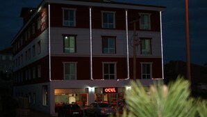 A multi-story hotel with a red and white facade, a visible entrance, and a sign that reads "otel". - Evrim Hotel (Hacibektas)