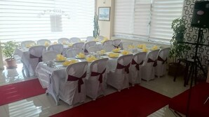 A banquet hall with round tables covered in white tablecloths and yellow centerpieces, arranged in rows. - Evrim Hotel (Hacibektas)