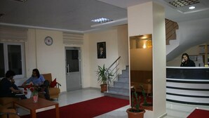 A hotel lobby with a reception desk, a staircase, and a seating area with a red carpet. - Evrim Hotel (Hacibektas)