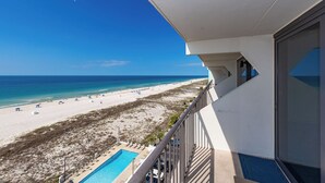A balcony with a view of a beach and a swimming pool. - BEACH FRONT! Condo in HIGH Demand! (Gulf Shores)