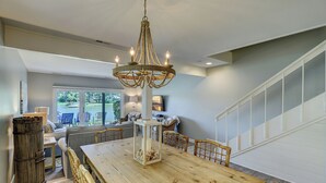 A spacious dining area with a wooden table and chairs, a chandelier, and a view of a lake through large windows.