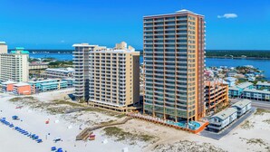 A beachfront hotel with multiple high-rise buildings, a sandy beach with umbrellas, and a clear view of the ocean. - Phoenix Gulf Shores 803 (Gulf Shores)