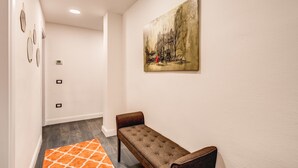 Un pasillo con un banco, un cuadro en la pared y una alfombra estampada.