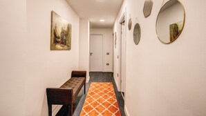 Un pasillo con un banco, un tapiz estampado y espejos en la pared.