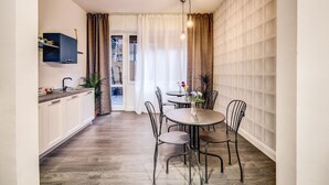 Una cocina compacta con armarios blancos, encimera oscura y una lámpara colgante.