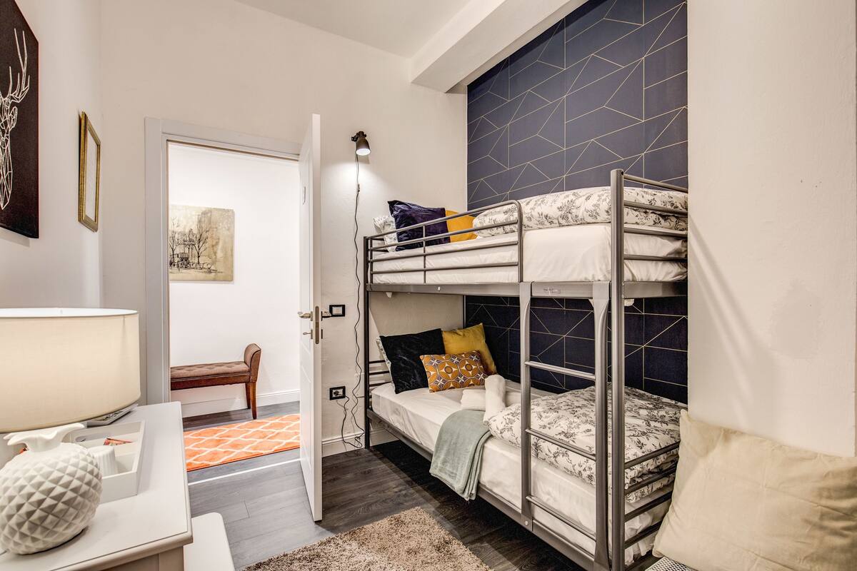 Habitación pequeña con literas, un escritorio con lámpara y una silla.