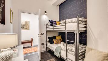 Habitación pequeña con literas, un escritorio con lámpara y una silla.