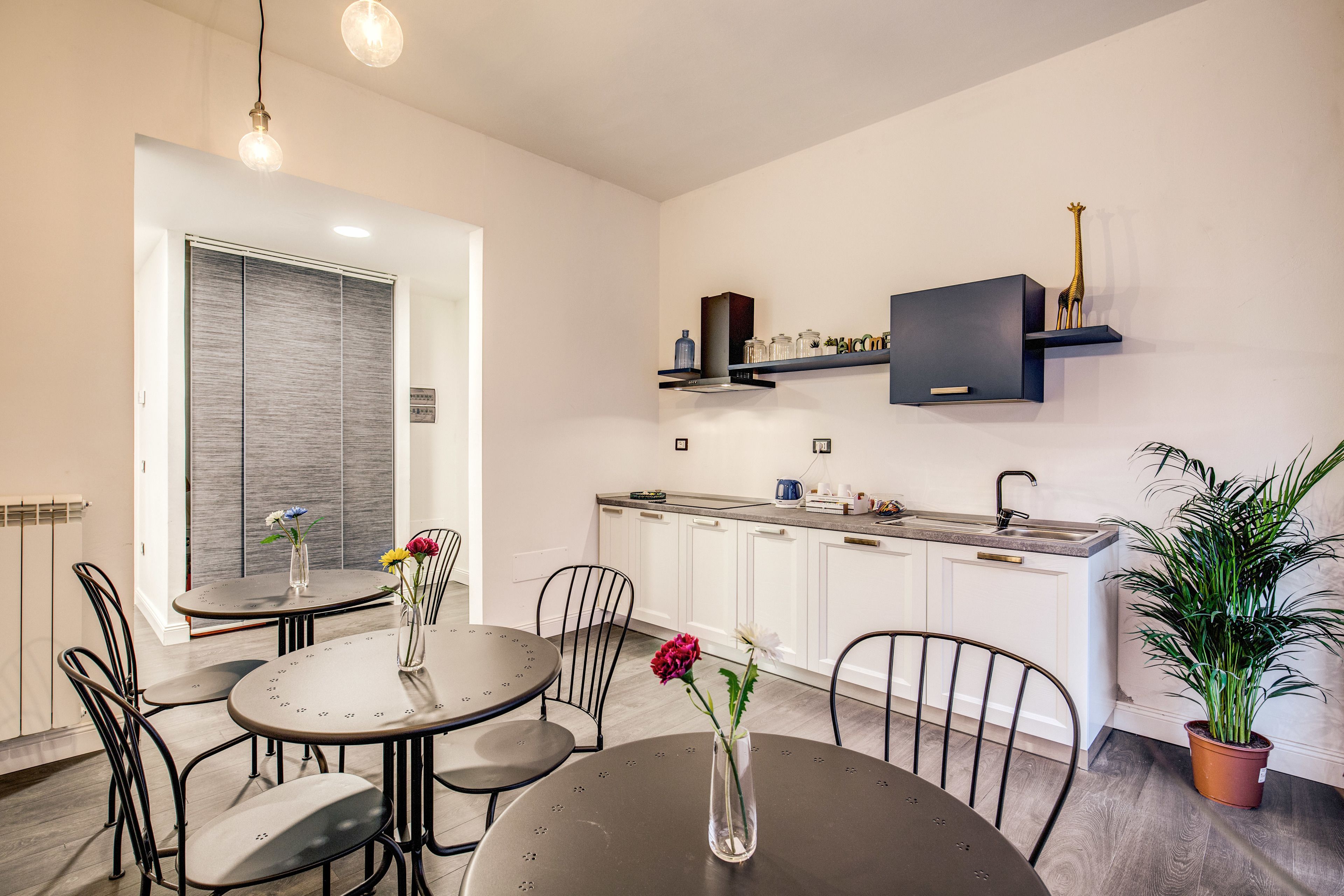 A modern kitchen with white cabinets, a built-in oven, and a black shelf with decorative items.