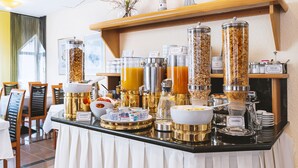 A breakfast buffet with various food items and beverages, including yogurt, cereal, and orange juice. - Hotel am Stadtgarten (Radolfzell am Bodensee)