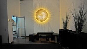 A modern interior with a circular light fixture, a bench, and potted plants. - Hotel am Stadtgarten (Radolfzell am Bodensee)
