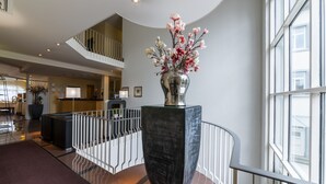 A spacious lobby with a large vase of flowers, a staircase, and a reception area. - Hotel am Stadtgarten (Radolfzell am Bodensee)