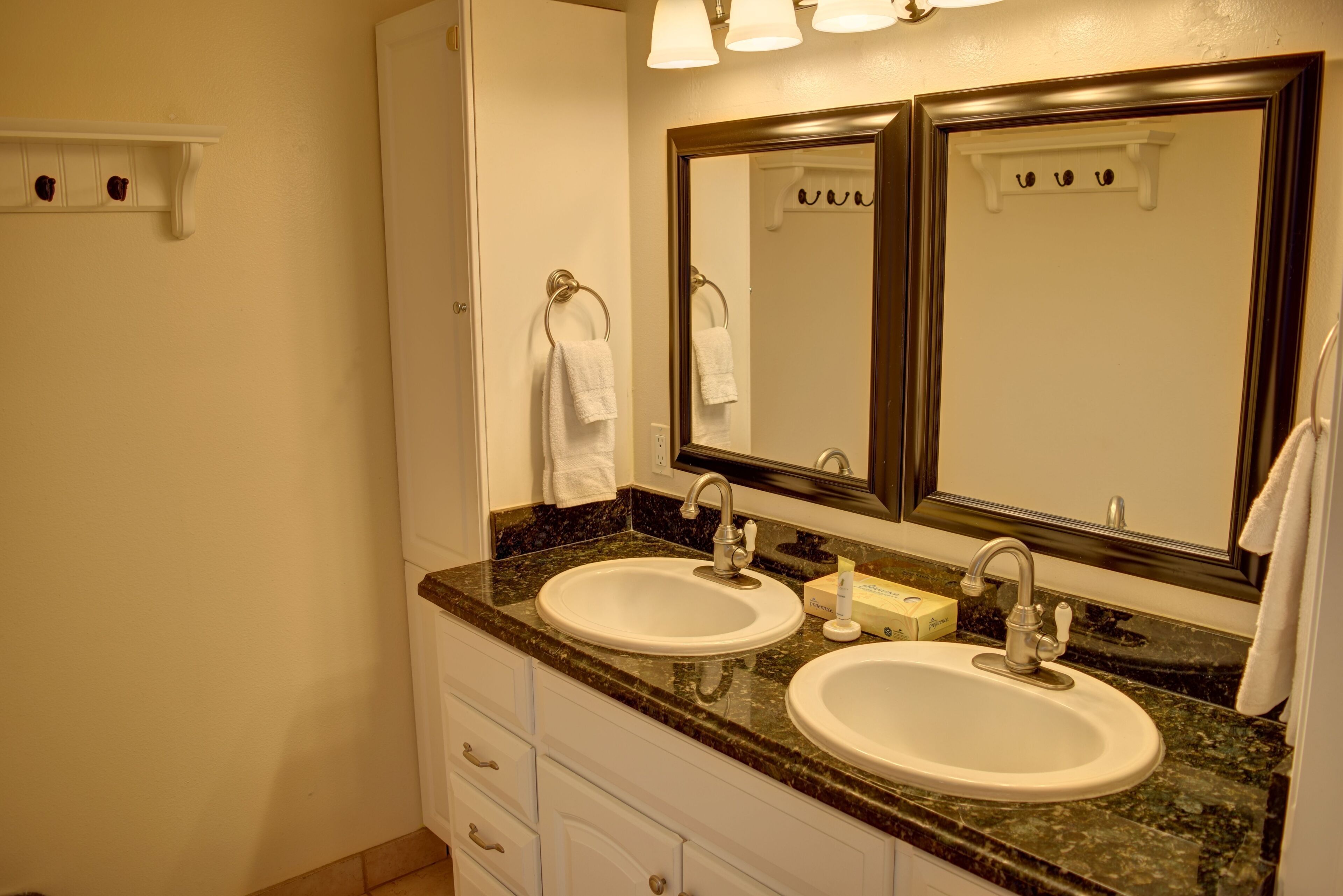 A bathroom with two sinks, a large mirror, and a towel rack.