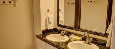 A bathroom with two sinks, a large mirror, and a towel rack.