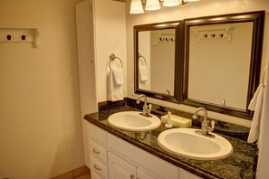 Un baño con dos lavamanos, un espejo grande y un perchero para toallas.