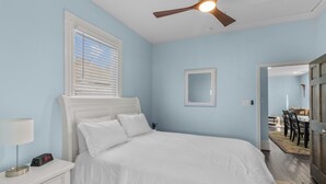 Ein Schlafzimmer mit Bett, Nachttisch, Lampe und Deckenventilator.