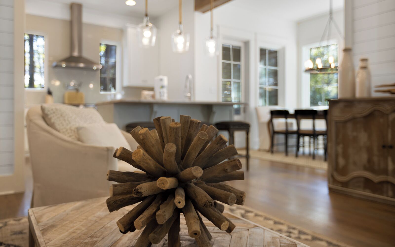 A modern living room with a central wooden sculpture, a sofa, and a dining area in the background.