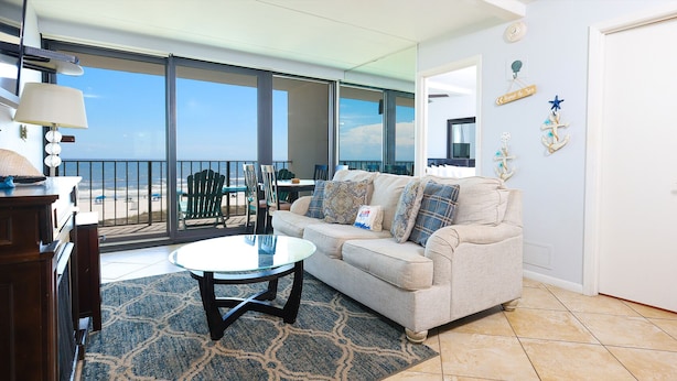 A living room with a glass table, a sofa, and a view of the beach. - PREMIUM! ~ BEACH FRONT ~ 2 Bedroom ~ (Gulf Shores)