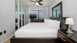 A hotel room with a bed, a television, a ceiling fan, a nightstand, and a view of the ocean. - PREMIUM! ~ BEACH FRONT ~ 2 Bedroom ~ (Gulf Shores)