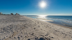 A wide beach with footprints, a clear sky, and buildings in the background. - PREMIUM! ~ BEACH FRONT ~ 2 Bedroom ~ (Gulf Shores)