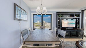 Un comedor con vista a la playa, un candelabro y un televisor sobre un mueble.