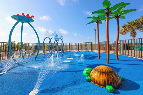 A water play area with a turtle sculpture, fountains, and palm trees. - The Oasis at Orange Beach, formerly known as Phoenix West II, Unit 2602 (Orange Beach)
