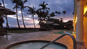 A hot tub surrounded by palm trees and a pool area during twilight. - 6 th floor ocean front condo Outstanding Views! Weekly discounts available  (Lahaina)